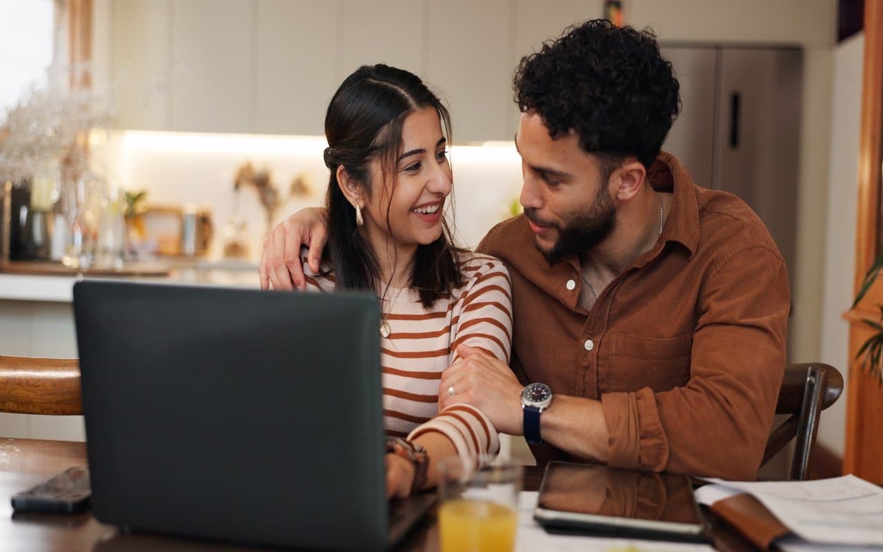 Couple Researching Homes in Brevard County Florida Couple reviewing home buying information on a laptop while discussing real estate options together.