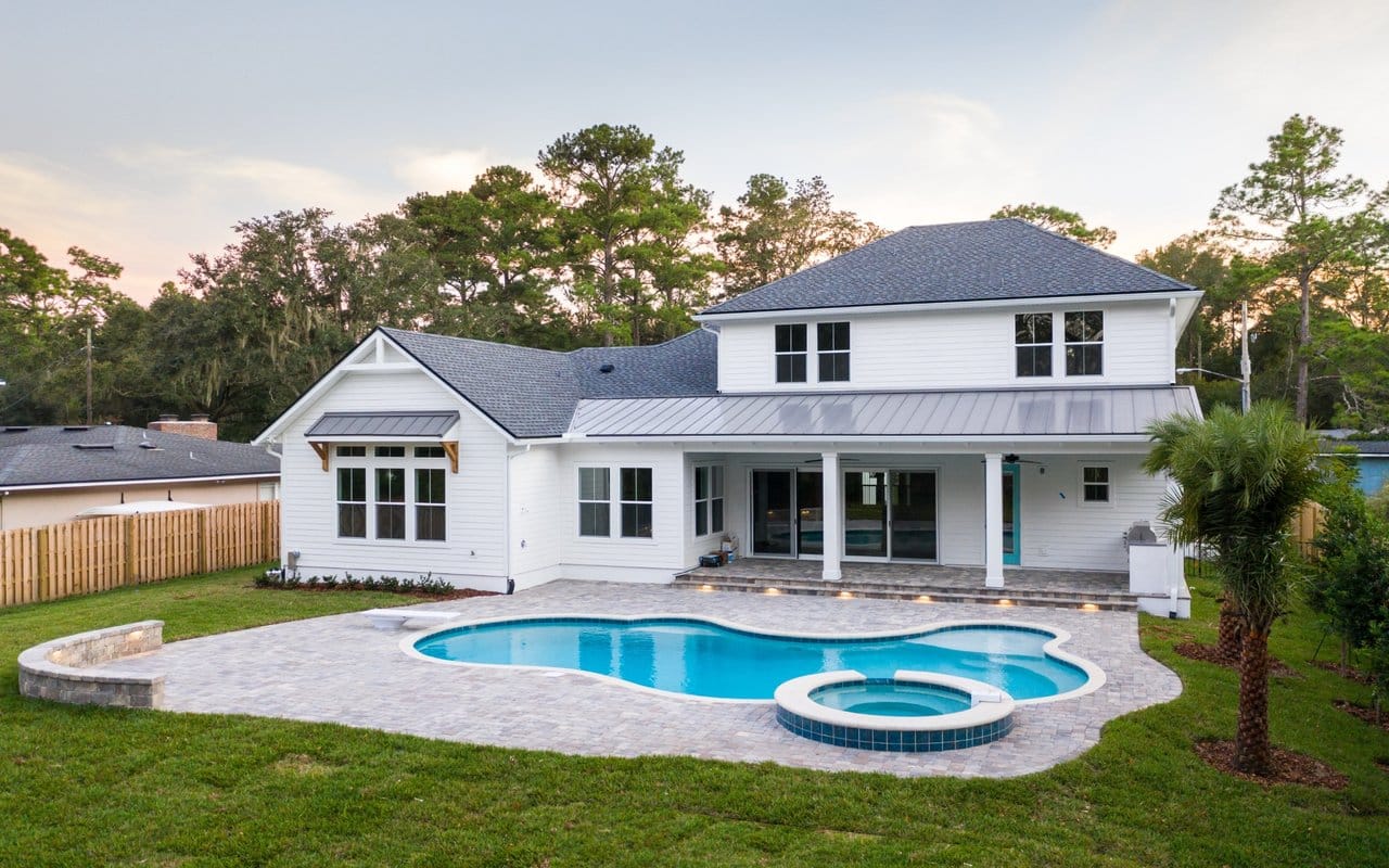 Luxury Home With Pool and Spa Rear exterior of a luxury home featuring a custom swimming pool, spa, covered patio, and landscaped backyard.