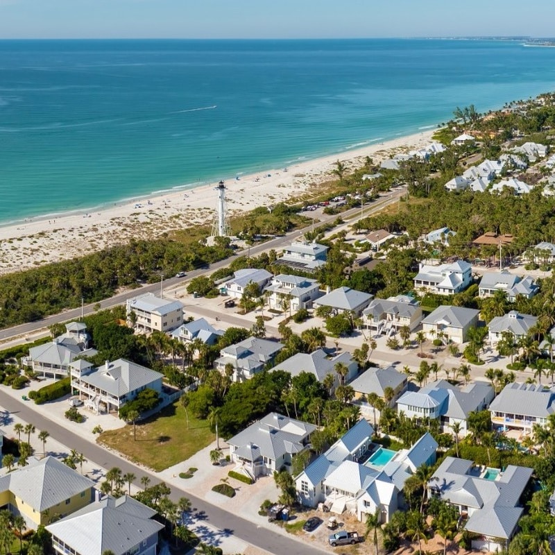 space coast beachfront residential community with homes, palm trees, and a long sandy shoreline.